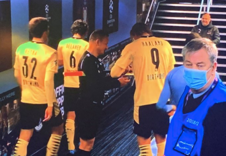 Erling Haaland autographing a red card and yellow card for an assistant referee after the Manchester City-Dortmund game